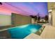 A backyard pool with travertine tile, a waterfall feature wall, and lounge seating in the background at 8038 E Clarendon Ave, Scottsdale, AZ 85251