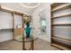 Bright walk-in closet features custom shelving, drawers, and a glass table with an arrangement of flowers at 8038 E Clarendon Ave, Scottsdale, AZ 85251
