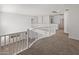 Spacious upstairs loft with neutral carpeting and white railings overlooks the downstairs area at 9051 W Iona Way, Peoria, AZ 85383