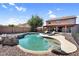 Backyard view of private pool with rock features, lounge chairs, and desert landscaping in a fenced yard at 941 E Stirrup Ln, San Tan Valley, AZ 85143