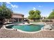 Backyard view of private pool with rock features, lounge chairs, and desert landscaping in a fenced yard at 941 E Stirrup Ln, San Tan Valley, AZ 85143