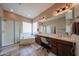 Large bathroom with a soaking tub, a glass-enclosed shower, dual sinks, and wood cabinets at 10465 E Knowles Ave, Mesa, AZ 85209