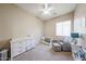 Neutral-toned bedroom with a vaulted ceiling, crib, glider, changing table, and window at 10465 E Knowles Ave, Mesa, AZ 85209