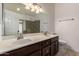 Bathroom with dual sinks, dark wood cabinetry, large mirror, and walk-in shower with decorative tile accents at 1063 W Vaughn St, Tempe, AZ 85283