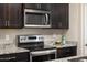 Close-up of modern kitchen with stainless steel oven and microwave above granite countertops and dark wood cabinets at 1255 N Arizona Ave # 1013, Chandler, AZ 85225