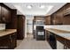 Kitchen with dark wood cabinets and black appliances at 12842 S Wakial Loop, Phoenix, AZ 85044