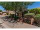 The front of the house has mature trees and bushes, rock landscaping, and a sidewalk at 1628 E Aspen Ave, Buckeye, AZ 85326