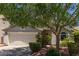 Charming single-Gathering home featuring a well-manicured front yard, mature trees, and a two-car garage at 1628 E Aspen Ave, Buckeye, AZ 85326