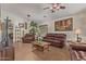 Cozy living room featuring leather furniture, a ceiling fan, and a large framed painting at 1628 E Aspen Ave, Buckeye, AZ 85326