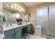 Bathroom featuring dual sinks, vanity, framed mirrors, a walk-in shower with glass doors, and modern lighting at 17812 W Primrose W Ln, Surprise, AZ 85374