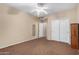 Spacious bedroom with carpet flooring, a ceiling fan, closet, and wood furniture, offering comfort and functionality at 17812 W Primrose W Ln, Surprise, AZ 85374