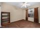 Neutral bedroom featuring a ceiling fan, carpet, and a large window with decorative curtains for natural light at 17812 W Primrose W Ln, Surprise, AZ 85374