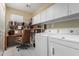 Functional laundry room with washer, dryer, built-in storage, and a desk for added convenience at 17812 W Primrose W Ln, Surprise, AZ 85374