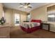 Spacious main bedroom with a ceiling fan, access to the bathroom, and a cozy bed at 17812 W Primrose W Ln, Surprise, AZ 85374