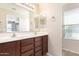 Bathroom with double sinks, wood cabinets, and natural light coming from the window at 21182 E Stonecrest Dr, Queen Creek, AZ 85142