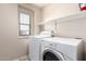 Bright laundry room with a white washer and dryer, a window and storage shelf at 21182 E Stonecrest Dr, Queen Creek, AZ 85142