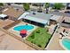 Backyard oasis featuring a sparkling blue pool, lush lawn, covered patio, and a charming red umbrella at 2207 W Bentrup St, Chandler, AZ 85224