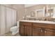 Well-lit bathroom features a double sink vanity, mosaic backsplash, and a shower with neutral tile and curtain at 22353 N 99Th Ln, Peoria, AZ 85383