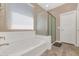 Bright bathroom with a soaking tub, glass shower, and a large window at 22353 N 99Th Ln, Peoria, AZ 85383