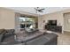 Comfortable living area with a ceiling fan, a sectional, and a sliding glass door to the outside patio at 22353 N 99Th Ln, Peoria, AZ 85383