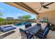 Covered outdoor patio with dining area and seating overlooking the pool and landscaped backyard at 22353 N 99Th Ln, Peoria, AZ 85383