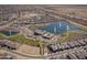 Aerial view of a community lake and recreational center with a pool and green spaces at 24847 N 175Th Dr, Surprise, AZ 85387