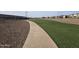 A serene community walking path winds through lush green spaces and manicured landscaping at 24847 N 175Th Dr, Surprise, AZ 85387