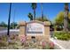 Entrance sign for The Raven Condominiums with colorful flowers and palm trees under a clear blue sky at 3434 E Baseline Rd # 204, Phoenix, AZ 85042