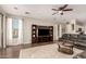 Spacious living room with modern TV console, dark laminate flooring, and large windows at 3532 W Mesquite Ave, San Tan Valley, AZ 85144