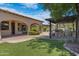 Expansive backyard with arched patio, outdoor kitchen, lush lawn, and mature landscaping at 4327 E Capricorn Pl, Chandler, AZ 85249