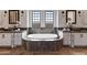 Bathroom featuring dual vanities, a soaking tub, tile accents, and sconce lighting at 4327 E Capricorn Pl, Chandler, AZ 85249