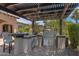 Outdoor kitchen under pergola features stainless steel grill, a stone countertop, mini-fridge and bar seating at 4327 E Capricorn Pl, Chandler, AZ 85249