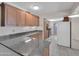 Well-lit kitchen featuring granite countertops, wood cabinetry, and modern appliances, designed for functionality and style at 4509 E Joan De Arc Ave, Phoenix, AZ 85032