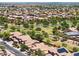 Expansive aerial view of a well-maintained neighborhood with lush green spaces and uniform rooftops at 46141 W Rainbow Dr, Maricopa, AZ 85139