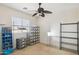 Bedroom featuring a ceiling fan, large window, and ample storage with metal shelving units at 46141 W Rainbow Dr, Maricopa, AZ 85139
