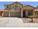 Inviting two-story home featuring a well-manicured front yard with mature palm trees and a three-car garage at 46141 W Rainbow Dr, Maricopa, AZ 85139