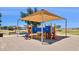Outdoor playground features a covered playset with slides, climbers, and benches in a park at 46141 W Rainbow Dr, Maricopa, AZ 85139