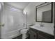 Bathroom with shower and tub combination, plus gray vanity with sink and dark-framed mirror at 53925 W Stallion Rd, Maricopa, AZ 85139