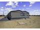 This shows a ground-level view of a small home with neutral siding and a gravel foundation at 53925 W Stallion Rd, Maricopa, AZ 85139