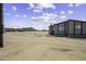 Exterior shot of a simple, manufactured home on a vast, sandy lot with minimal landscaping and open space at 53925 W Stallion Rd, Maricopa, AZ 85139