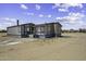 The image displays a manufactured home with a small porch, set on a flat, sandy lot under a partly cloudy sky at 53925 W Stallion Rd, Maricopa, AZ 85139