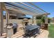 Inviting outdoor dining area featuring a built-in grill, fireplace, and a pergola for shade at 6712 W Miner Trl, Peoria, AZ 85383