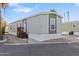 Charming manufactured home with brown accents, lush landscaping, and covered parking spaces at 701 S Dobson Rd # 203, Mesa, AZ 85202