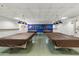 A game room with covered pool tables, overhead lighting, and a display shelf showcasing trophies at 701 S Dobson Rd # 203, Mesa, AZ 85202