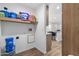 Laundry room features a utility sink, storage shelves, and wood look flooring at 701 S Dobson Rd # 203, Mesa, AZ 85202