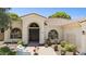 Inviting front entry with custom wood door, arched windows and manicured landscaping with mature trees at 7032 N 2Nd Ave, Phoenix, AZ 85021