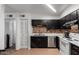 Efficient kitchen layout featuring black cabinets, a brick backsplash, and white appliances at 830 S Dobson Rd # 86, Mesa, AZ 85202