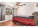 Cozy bedroom features wood-look flooring, ceiling fan, and a window with blinds and curtains at 8939 W Villa Rita Dr, Peoria, AZ 85382