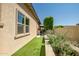 Well-maintained side yard with artificial turf, manicured shrubs, and a glimpse of an outdoor seating area at 9255 W Los Gatos Dr, Peoria, AZ 85383