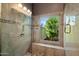 Tiled walk-in shower with integrated bench and window to the lush landscaping beyond at 10068 E San Salvador Dr, Scottsdale, AZ 85258
